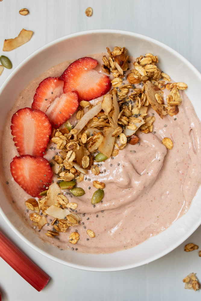 a strawberry smoothie bowl topped with granola and fresh strawberries