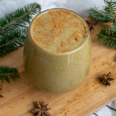 a glass of gingerbread smoothie surrounded by fresh pine and star anise.