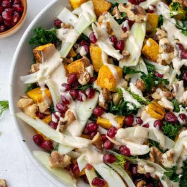 a large bowl of kale, squash and fennel salad and a small bowl of fresh pomegranate seeds.