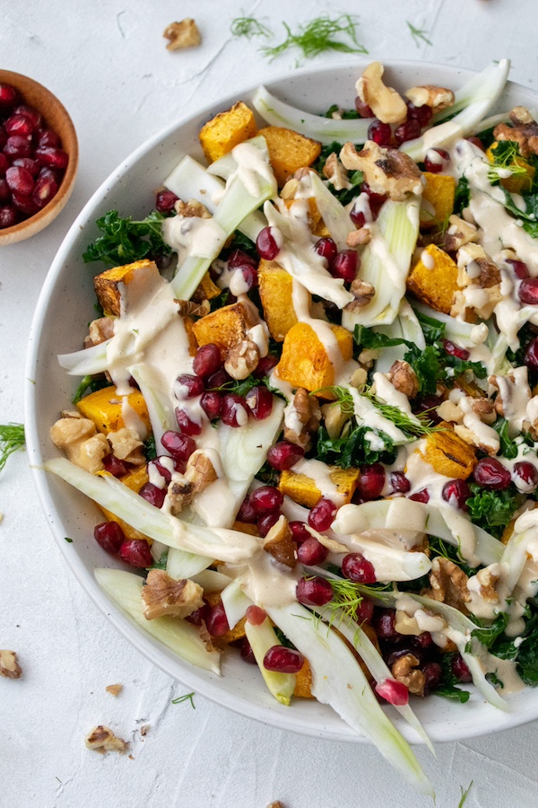 a large bowl of kale, squash and fennel salad and a small bowl of fresh pomegranate seeds.