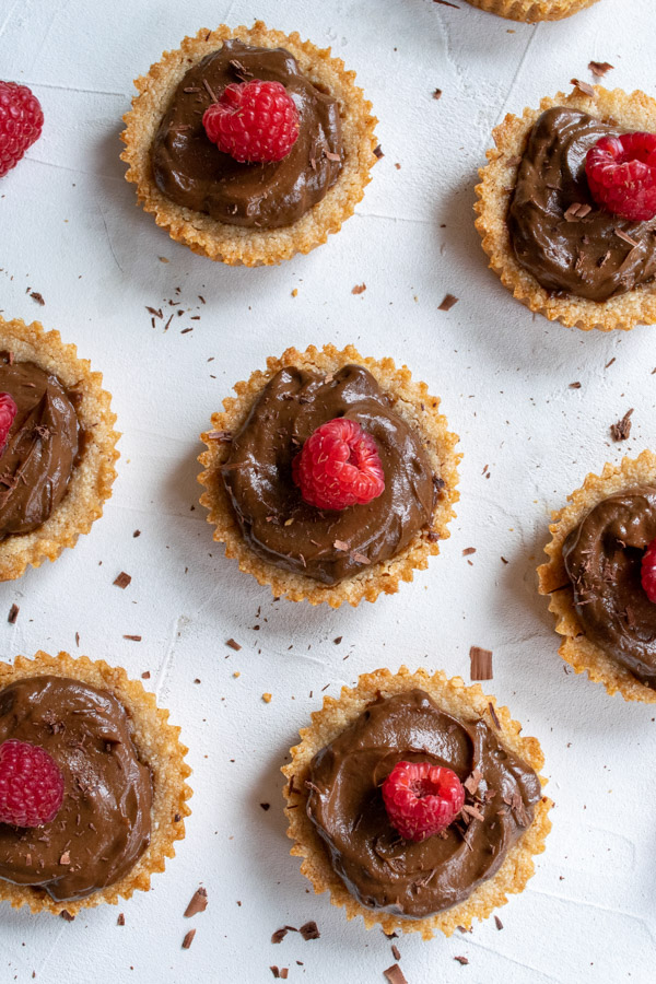chocolate avocado mousse tartlets topped with fresh raspberries and shaved dark chocolate