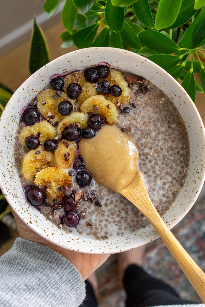 a bowl of chia pudding topped with caramelized bananas, blueberries and salted tahini caramel.
