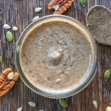 a jar of super seed pecan cashew butter surrounded by cashews, pecans and pumpkin seeds.