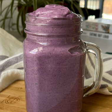 a glass jar filled with a lemon blueberry smoothie.