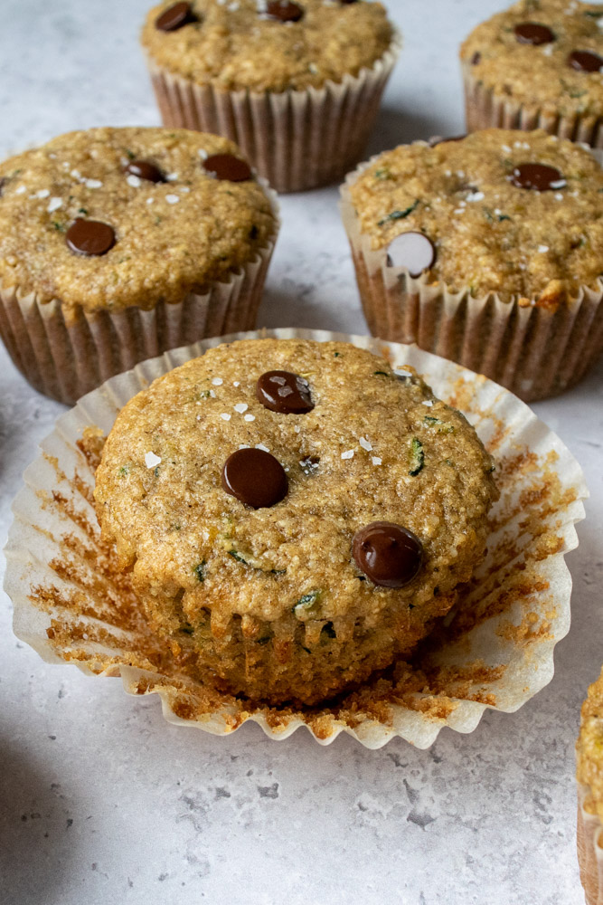 a close up of chocolate chip zucchini muffins topped with flaked sea salt.