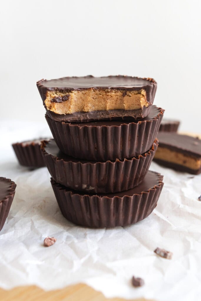 a stack of chocolate protein cookie dough cups on parchment paper.