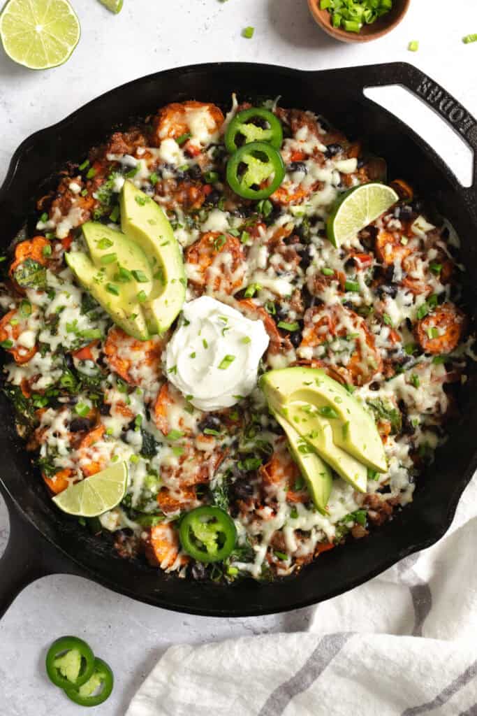 beef and sweet potato taco skillet topped with greek yogurt, jalapeño and lime slices.