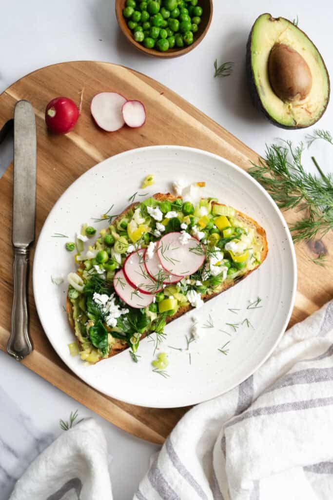 spring avocado toast on a white plate and cutting board.