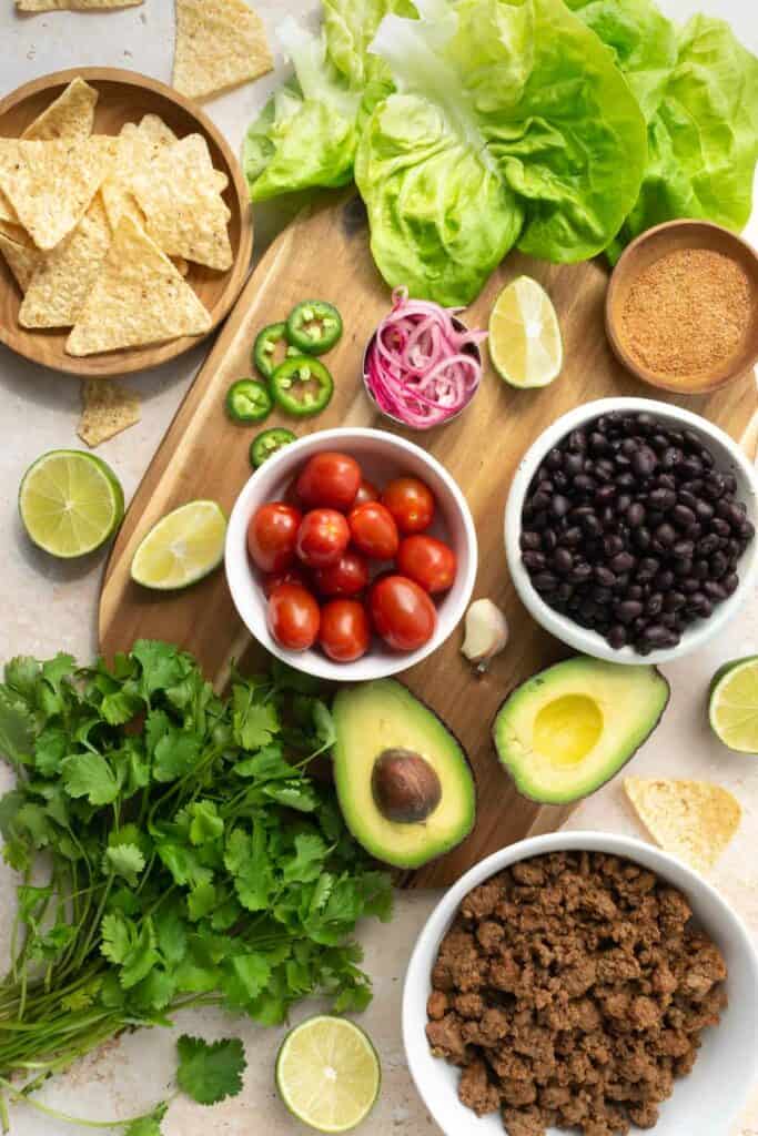 beef taco salad and avocado cilantro dressing ingredients on a wooden cutting board.