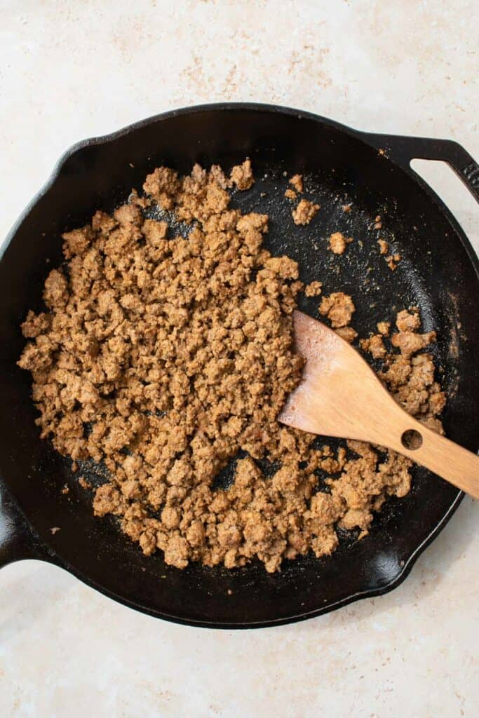 taco ground beef and a wooden spoon in a cast iron skillet.