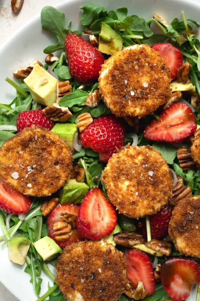 fried goat cheese and strawberry salad in a white bowl.