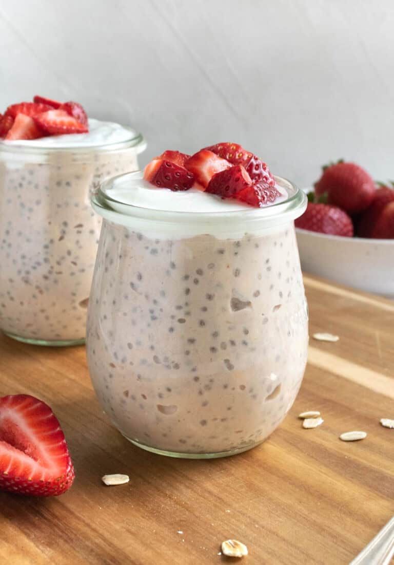 jars of strawberries and cream overnight oats topped with yogurt and strawberries.