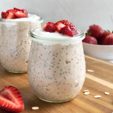 jars of strawberries and cream overnight oats topped with yogurt and strawberries.