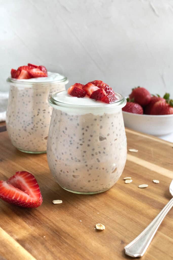 jars of strawberries and cream overnight oats topped with yogurt and strawberries.