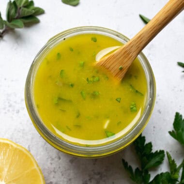 lemon herb vinaigrette with a wooden spoon, lemon and herbs.