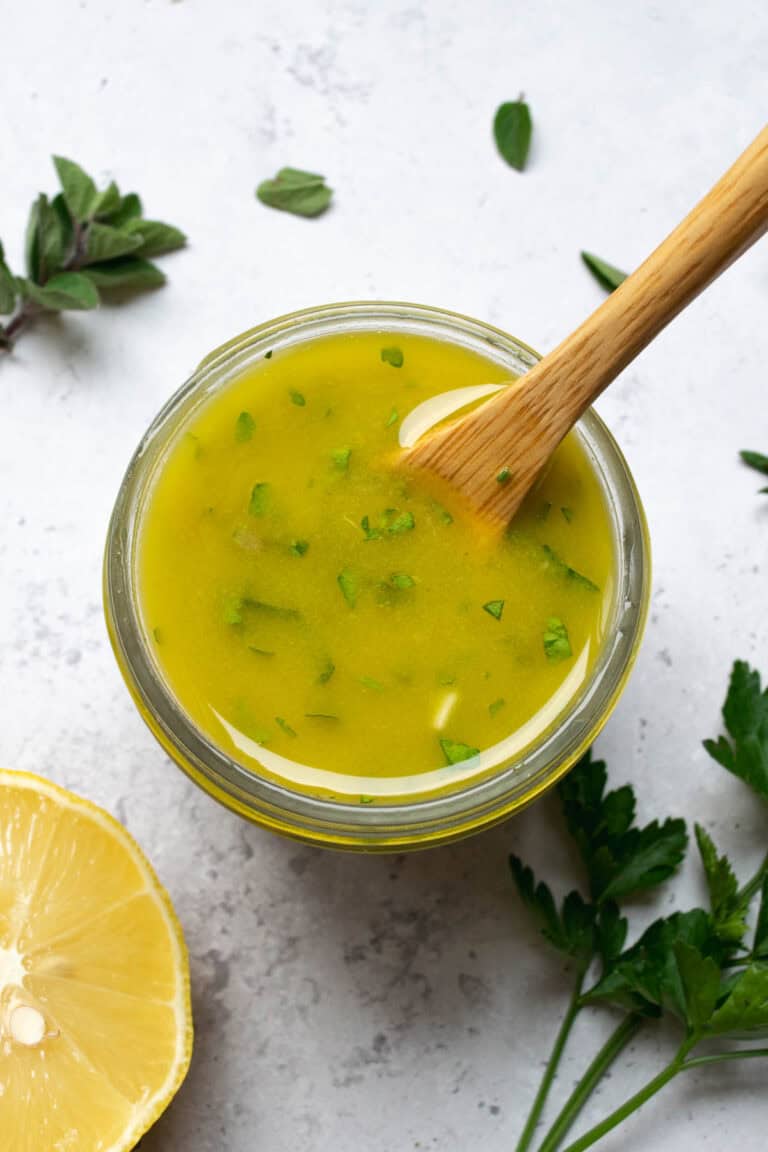 lemon herb vinaigrette with a wooden spoon, lemon and herbs.