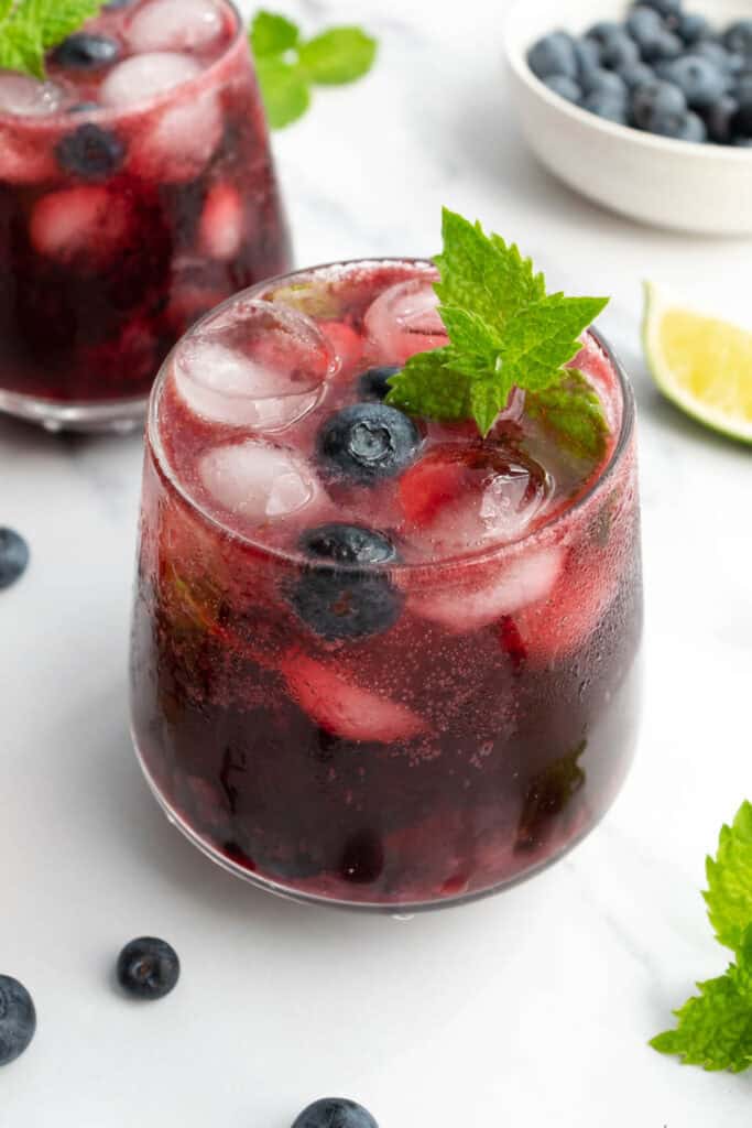 mocktails, a white bowl with blueberries and a lime wedge.