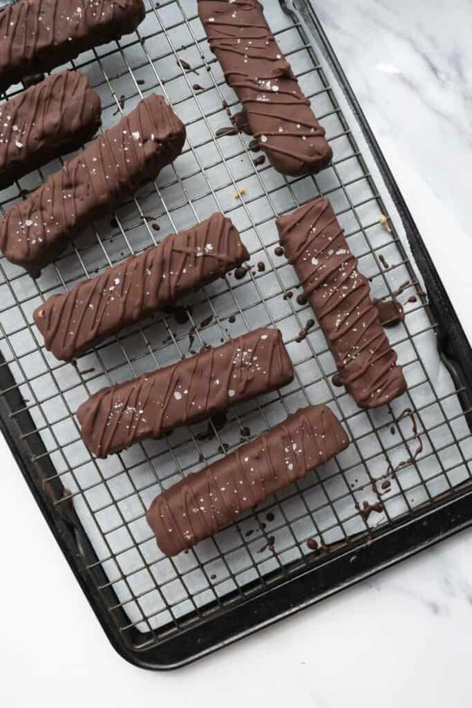 chocolate covered ice cream bars on a cooking rack and baking sheet.