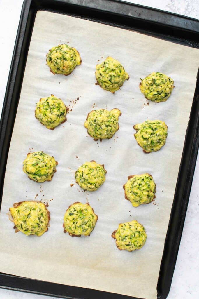 cooked zucchini bites on a baking sheet lined with parchment paper.