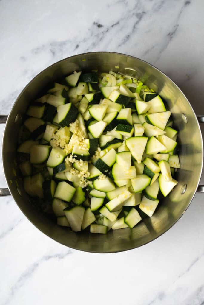 zucchini, minced garlic, and leek being sautéed.