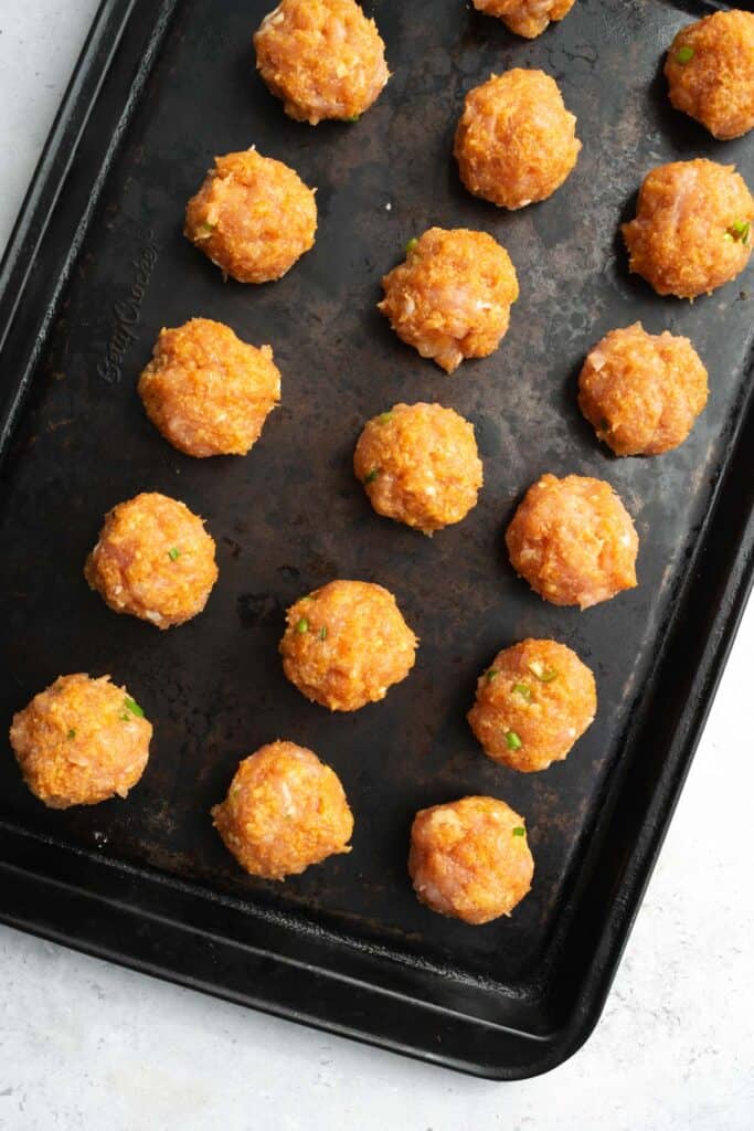 uncooked turkey meatballs on a baking sheet.