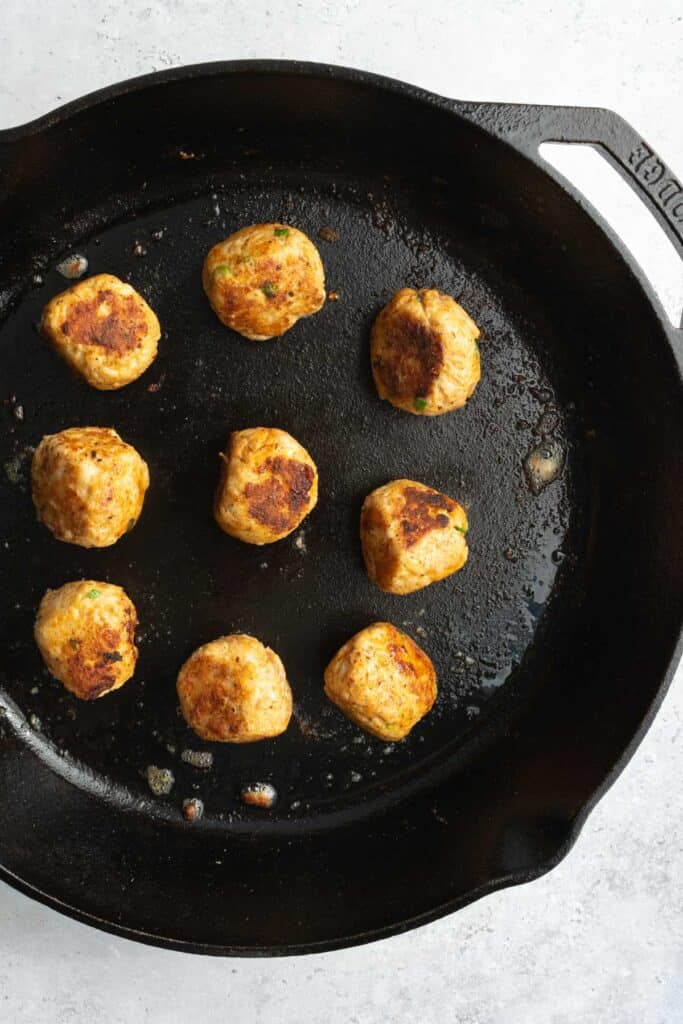 seared meatballs in a skillet.