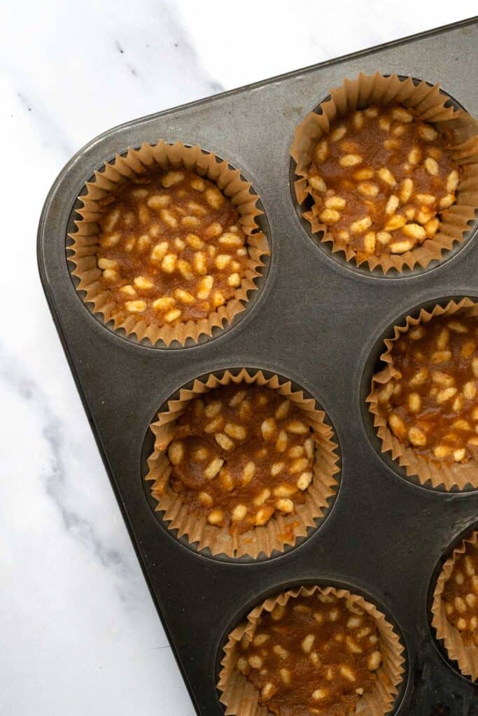 a muffin tin with liners filled with the pumpkin peanut butter mixture.