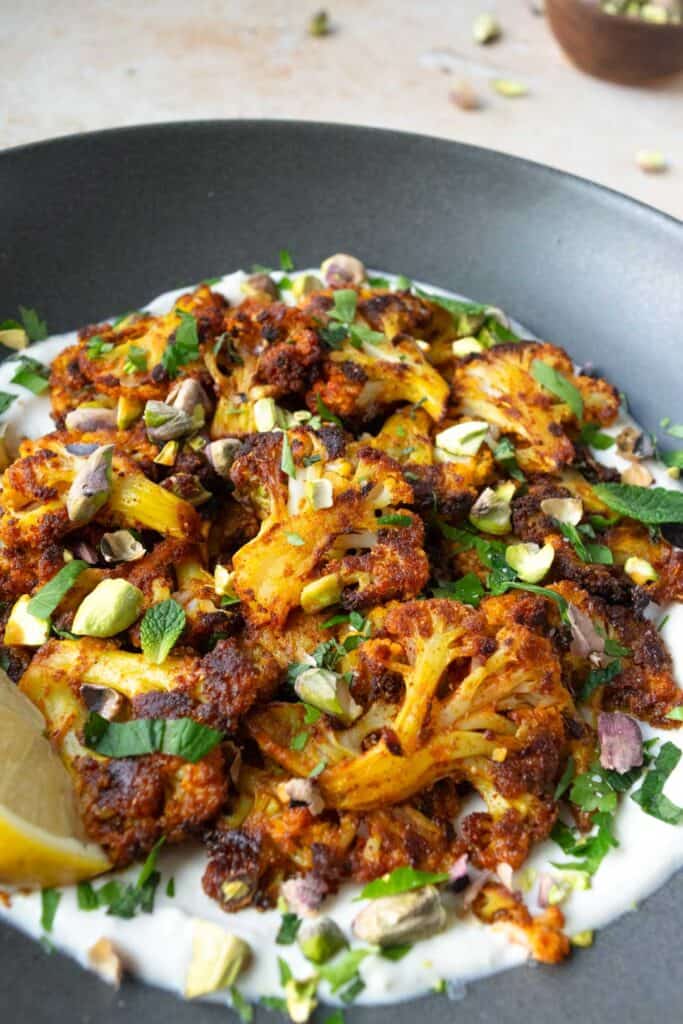 smashed cauliflower over yogurt with fresh herbs and pistachios