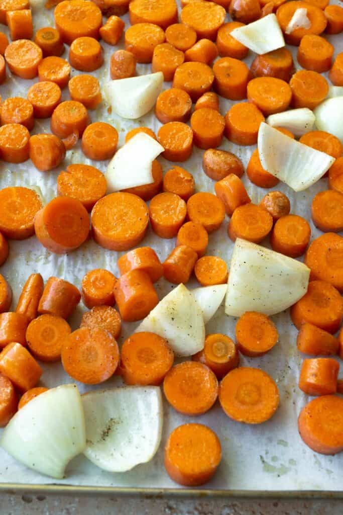 chopped carrots, onion and garlic on a baking sheet